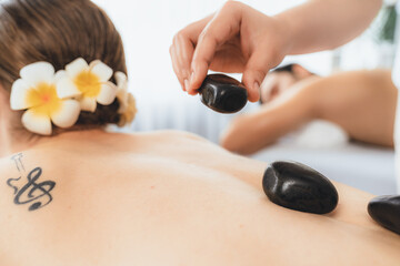 Closeup hot stone massage at spa salon in luxury resort with day light serenity ambient, blissful...