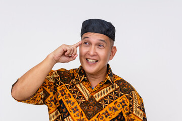 A Indonesian man wearing a batik shirt and a kopiah hat having a spur of the moment idea. Isolated on a white background.