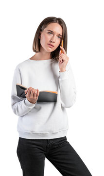 A woman in casual wear holding a book and a pencil, with a thoughtful expression, against a white background. Photography concept