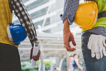 Helmet construction Engineer team. Men hands holding hardhat yellow work helmet in Civil Construction Engineering. Close up engineer man hold safety yellow worker helmet hard hat at Construction Site