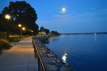 Stroll along a serene waterfront as the moon reflects off the calm waters, creating a shimmering pathway to the horizon, Generative AI