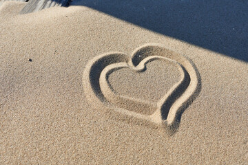 Fototapeta na wymiar Heart drawn in the sand on the beach. Symbol of love.