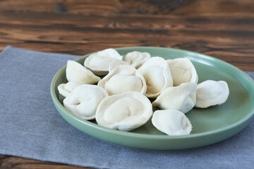 Meat dumplings on a green plate on a wooden background.