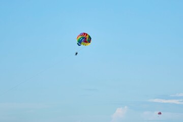Fototapeta na wymiar Parachute flying in bright colors as a summer entertainment. Beach holidays