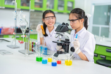 Two female scientists, a student, use a microscope to research a vaccine. On the table are beakers, experimental equipment, holding solution tubes. In the hospital lab Used for medicine