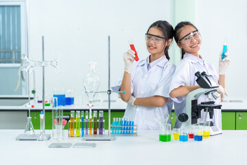 Two Asian scientists are doctors who produce COVID-19 medicines and vaccines in a biology lab. Use microscopes and beakers to conduct medical research and treat patients in hospitals.