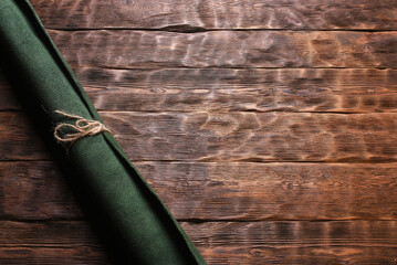 Green leather rolled up pieces scrolls on the brown flat lay table background. Top view.