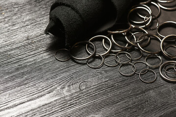 Leather piece and metal rings furniture on the wooden black table background. Leather craft concept. Top view.