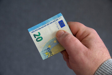 A hand holding a twenty euro bill