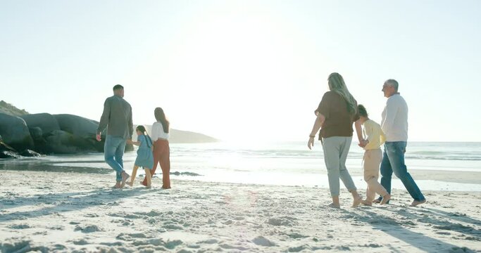 Happy family, holding hands and generations walking on beach, sunset and love with bonding on summer holiday. Dad, mom and kids on sea sand with grandparents, blue sky and relax in nature on vacation