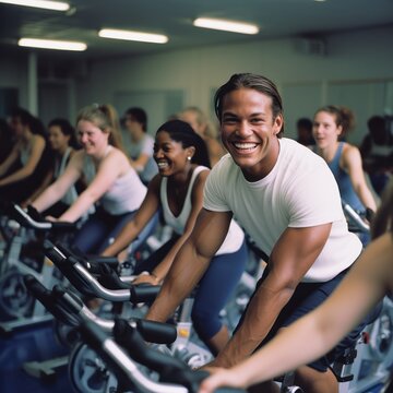 Fit people working out at spinning class in the gym, cycling a bike at gym, cardio training, exercising legs, wearing sports tights and top. Group of smiling friends at gym 