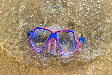 Visor sobre la playa, goggle anaranjado con azul para actividades acuáticas