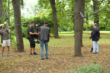 Five are standing in the park and shooting movie - obrazy, fototapety, plakaty