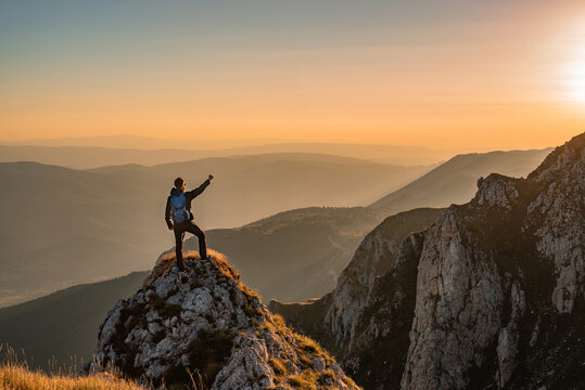 A man who hikers enjoys a break look at the top of the mountain at sunset adventure travel.