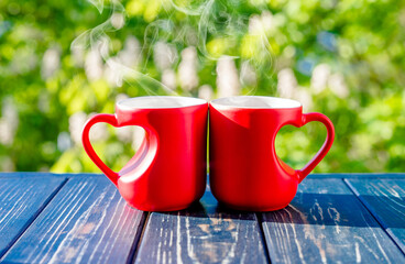 two heart shaped mugs with tea against the background of blossoming cherry
