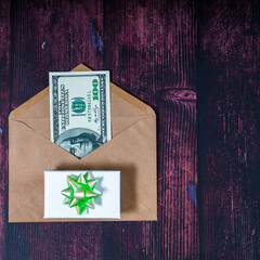 Dollars in the envelope with giftbox on a brown wooden table. Topview background with copyspace