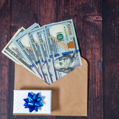 100 dollars banknotes in the envelope with giftbox on a wooden table. Topview background with copyspace