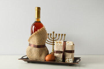 Matzo, egg, hanukkiah and bottle of wine on light background