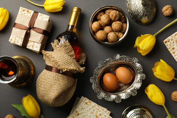 Matzo, nuts, eggs, bottle of wine and flowers on gray background, top view