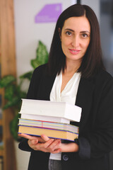 Woman reading and holding books in library. Portrait of college girl reading book in library