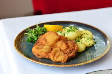Schnitzel with potatoes on a plate in a restaurant.