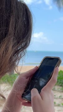 A girl is taking picture with her smartphone on a beach Young brunette woman makes video on the beach, selective focus. High quality 4k footage