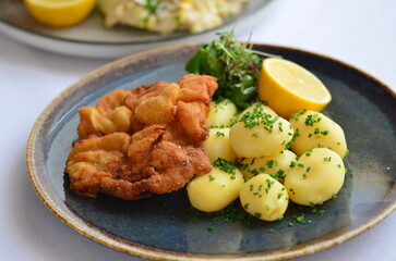 Schnitzel with potatoes on a plate in a restaurant.