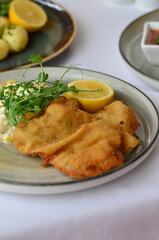 Wiener schnitzel with salad on a restaurant table.