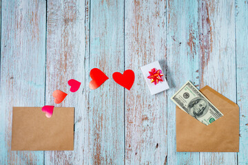 Paper cut red hearts, envelope and dollars on a wooden background. Topview with copyspace for St Valentines Day