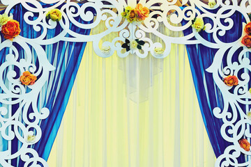 Wedding decor. White carved arch frame and flowers, azure curtains, orange tulle