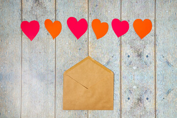 Paper cut red hearts and paper envelope on a wooden background. Topview with copyspace for St Valentines Day