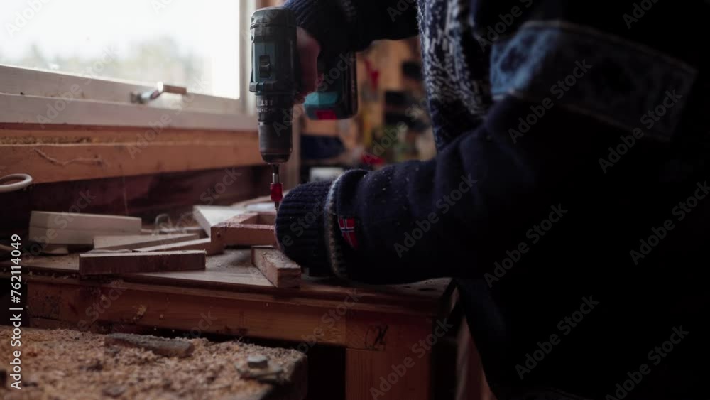 Poster carpenter using wireless screwdriver inside the workshop. close-up shot