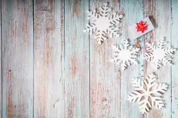 Snowflakes and a present with red ribbon on a light blue wooden background. Christmas winter flatlay with copyspace	