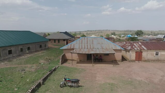 Aerial - Sideway drone of unpainted weathered houses in rural Nigerian village