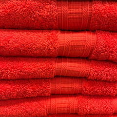 Red terry towels are stacked on a shelf. The background image.
