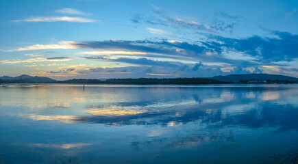 Fototapeta na wymiar Sunrise, clouds, blue sky and water - a perfect day