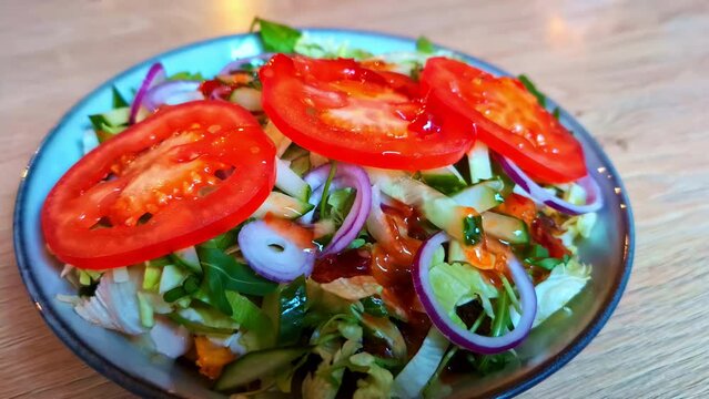 Pullback from fresh mediterranean salad with bright red tomato slices, red onions, cucumbers, and fresh lettuce