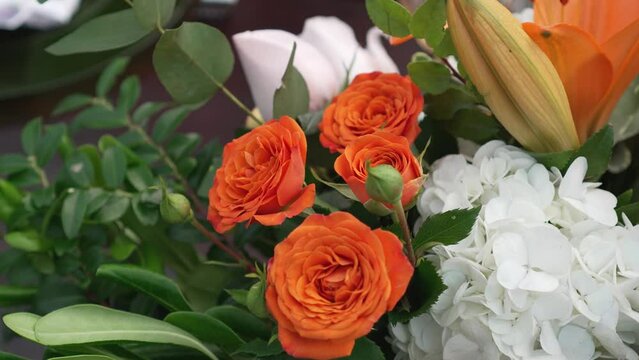 A bouquet of orange roses with green leaves. The roses are in full bloom and are arranged in a vase.