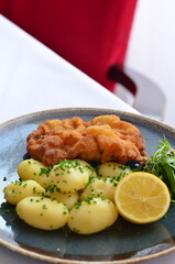 Schnitzel with potatoes on a plate in a restaurant.