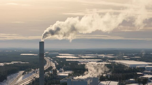 Smokestack emitting greenhouse gases against golden hour sky, telephoto aerial