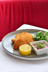 Wiener schnitzel with salad on a restaurant table.