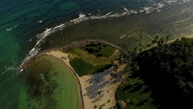 Overhead drone shot slowly descending down the Miami Beach peninsula as waves crush at its shores in Itea, in Central Greece.