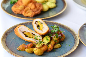 schnitzel stuffed with cheddar cheese, baked potato, baked potato, food served in a restaurant on a...