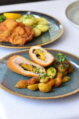 schnitzel stuffed with cheddar cheese, baked potato, baked potato, food served in a restaurant on a...