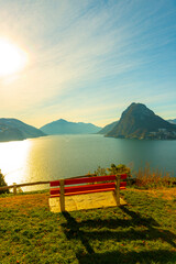 Bench on Lake Lugano and City with Mountain and Blue Sky in Park San Michele in Castagnola in Lugano, Ticino in Switzerland.