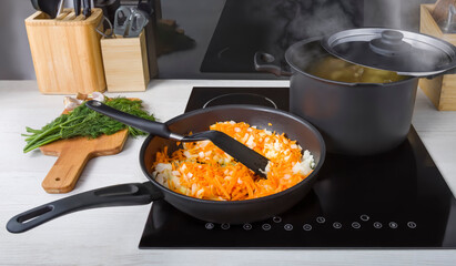 A frying pan with stewed vegetables and a saucepan with boiling broth on an electric glass-ceramic hob