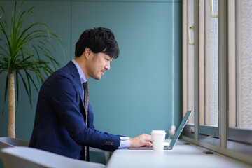 グリーンのオフィスとスーツとPCの男性