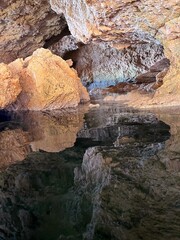 Cave rocks with surreal reflections in the sea water.