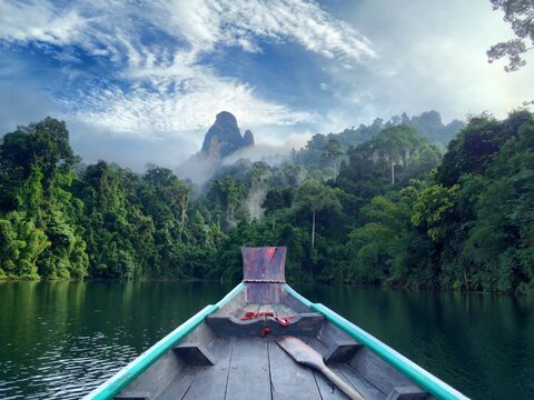 Boat bow leading into misty tropical lake with limestone karst &mdash; tranquil travel landscape