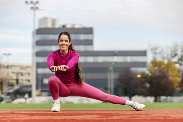 An athlete is stretching her legs at the stadium.